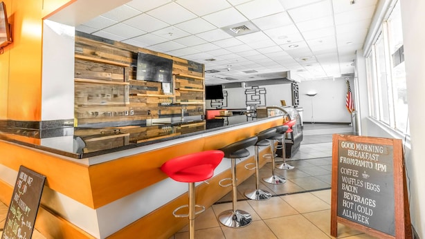 A breakfast bar with stools, a menu board, and a counter with a wooden panel design. - Ramada by Wyndham Hotel & Water Park (Kissimmee)