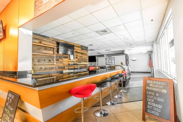 Un bar où l’on prend le petit-déjeuner, avec des tabourets, un tableau affichant le menu et un comptoir doté d’un panneau décoratif en bois.