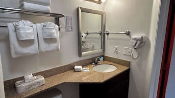 A bathroom with a sink, mirror, towel rack, and hairdryer.