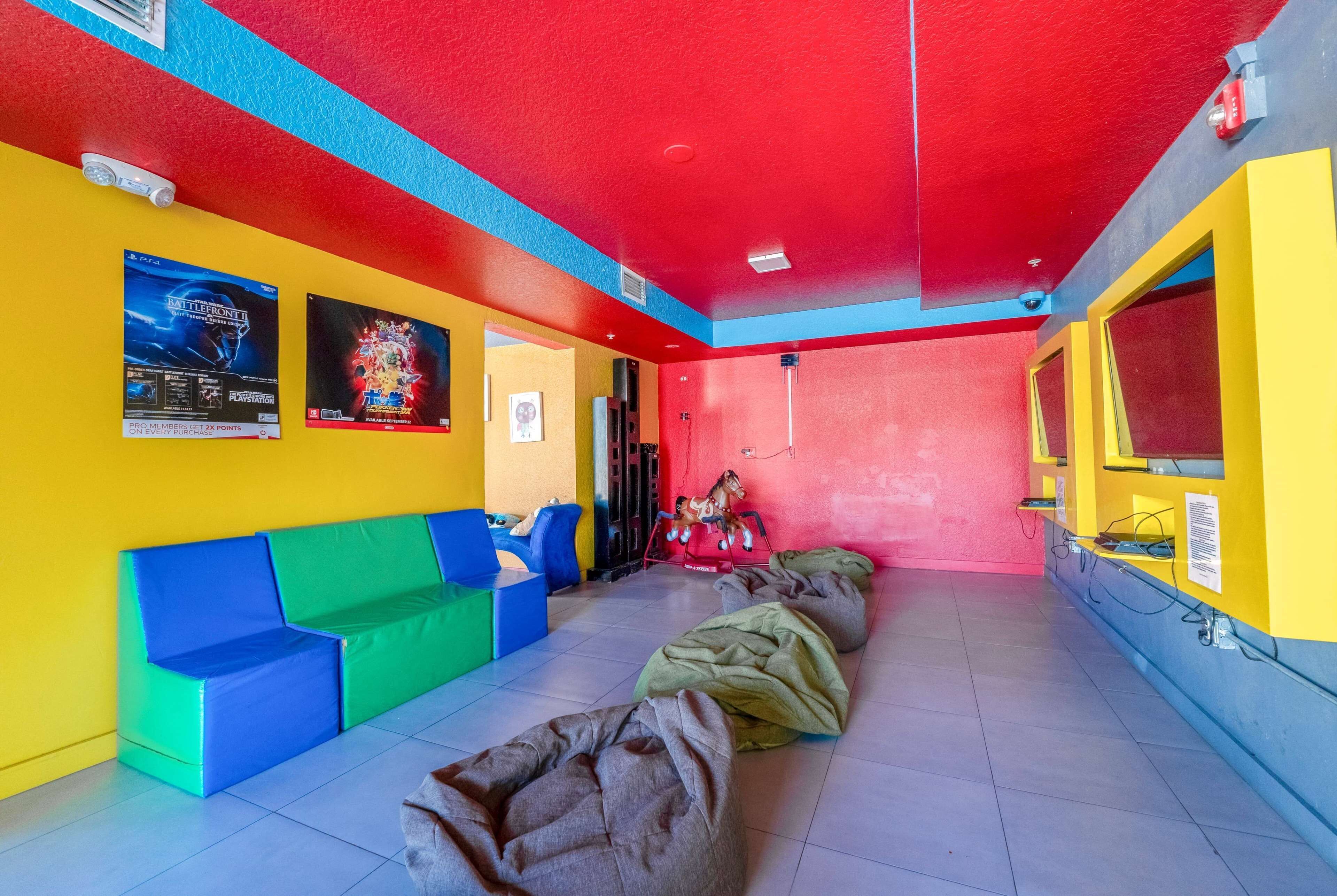 A brightly colored room with a red ceiling, yellow and blue walls, and a seating area with colorful cushions.