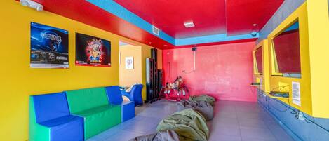 A brightly colored room with a red ceiling, yellow and blue walls, and a seating area with colorful cushions.