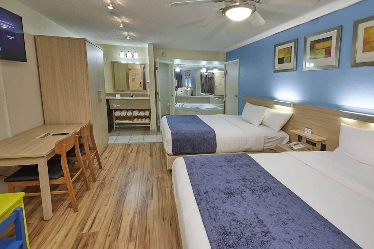Een hotelkamer met een bed, nachtkastje, bureau, stoelen en een spiegel.