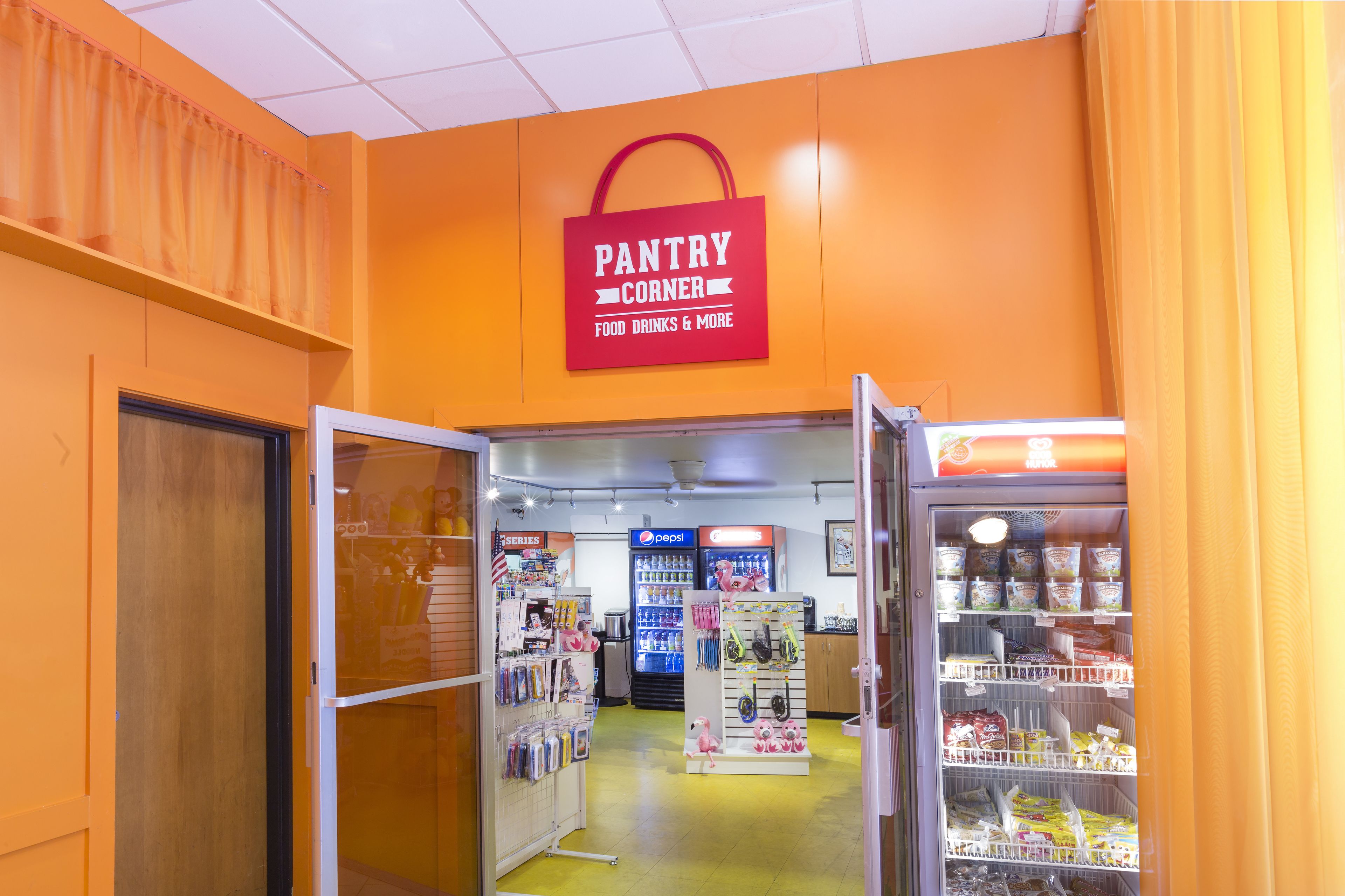 A pantry corner with food and drinks, a Pepsi refrigerator, and a display of snacks.