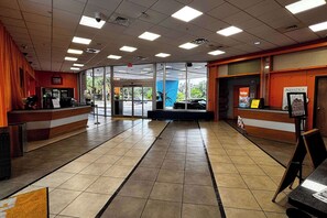 A spacious interior with a reception area, a counter, and a view of the outside through large windows. - Ramada by Wyndham Hotel & Water Park (Kissimmee)