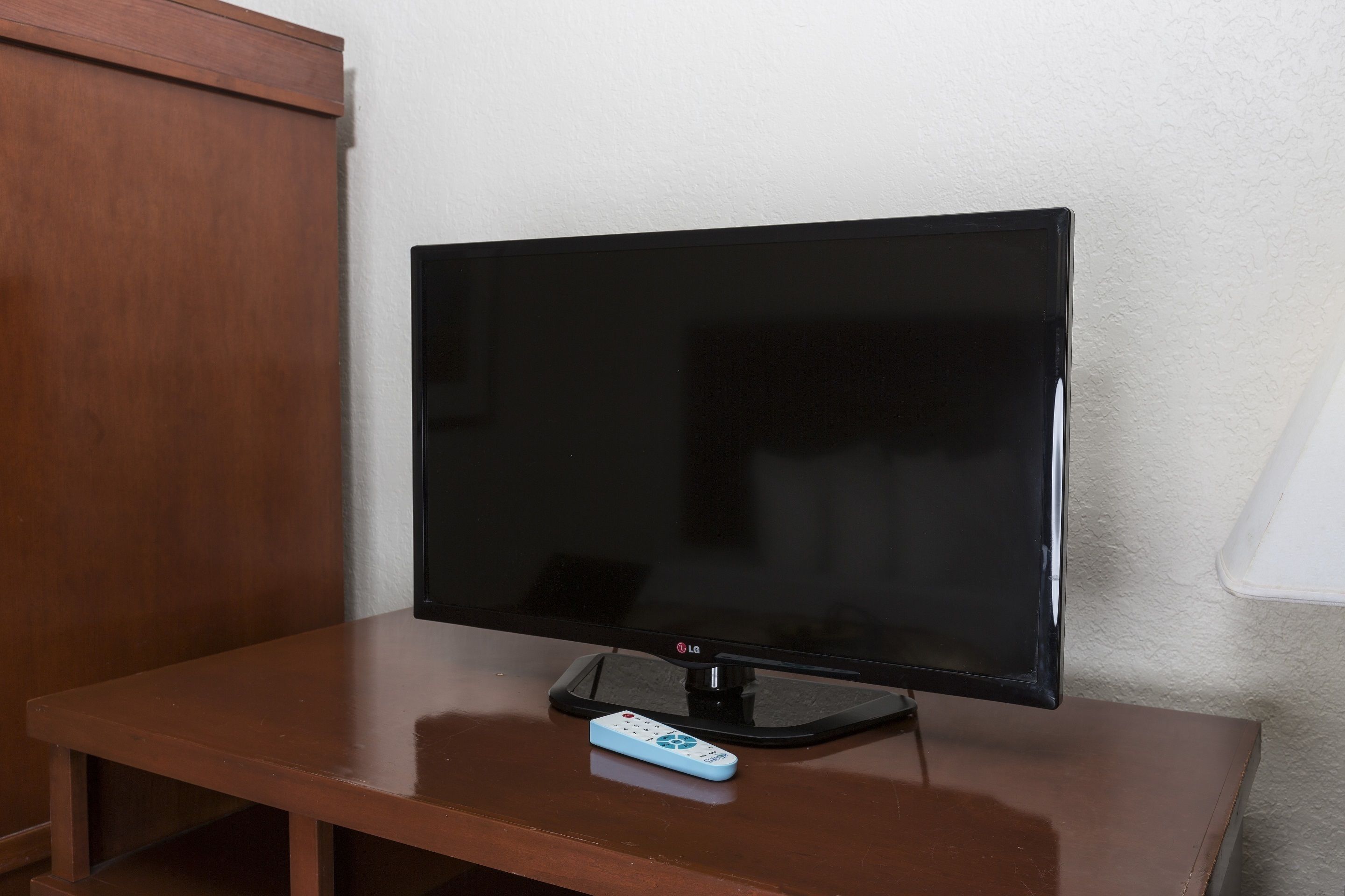 A flat-screen TV on a wooden table with a remote control.
