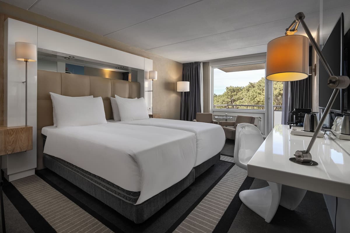 Een hotelkamer met een groot bed, een bureau, een stoel en een televisie.