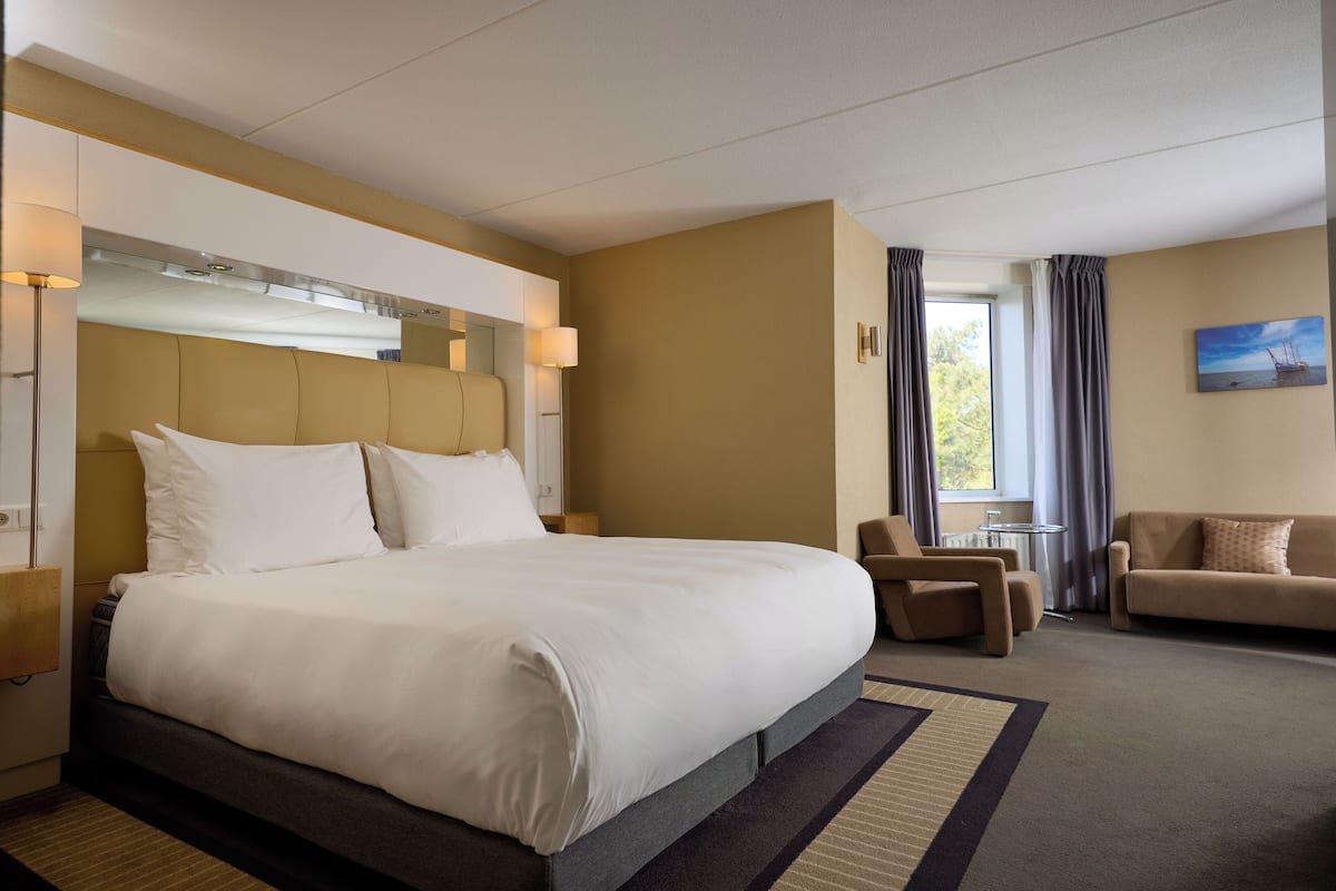 Een hotelkamer met een groot bed, een bank, een stoel en een kleine tafel.