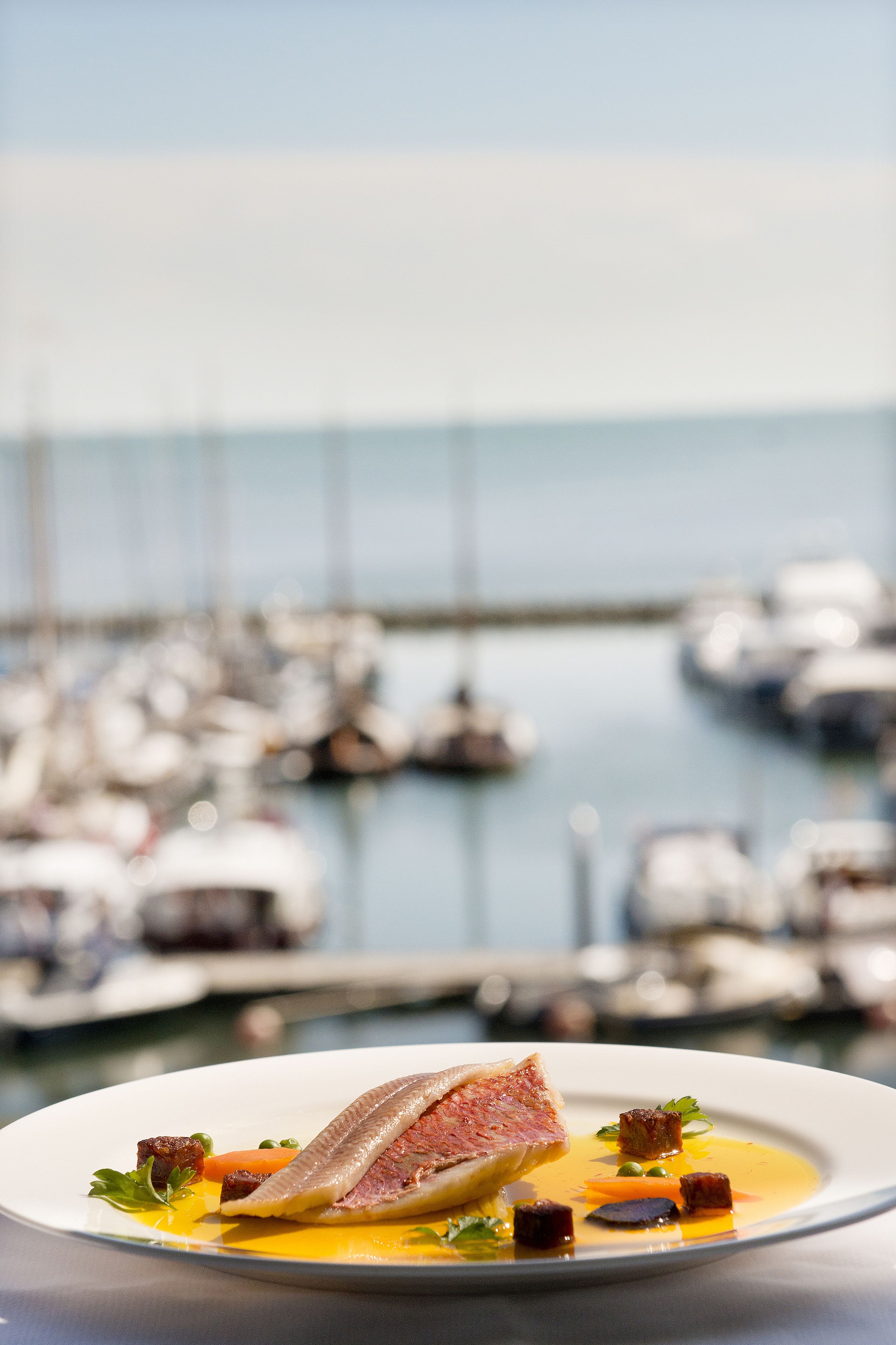Un plato de mariscos con vista a un puerto deportivo.