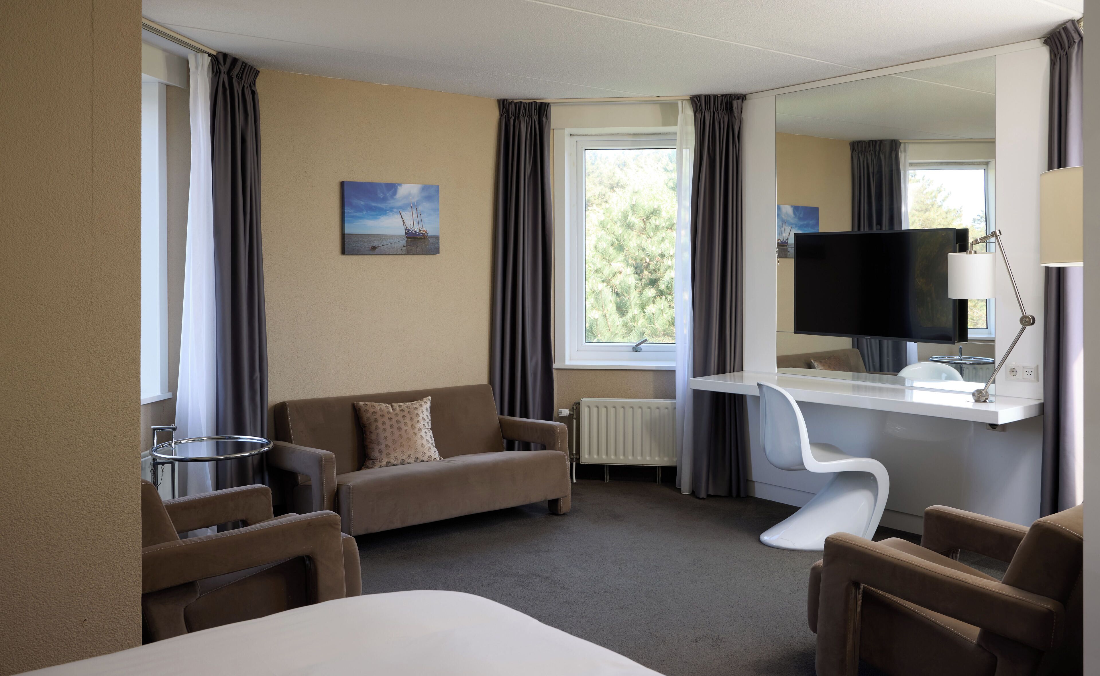 A hotel room with a bed, a desk with a computer, a sofa, and a TV.