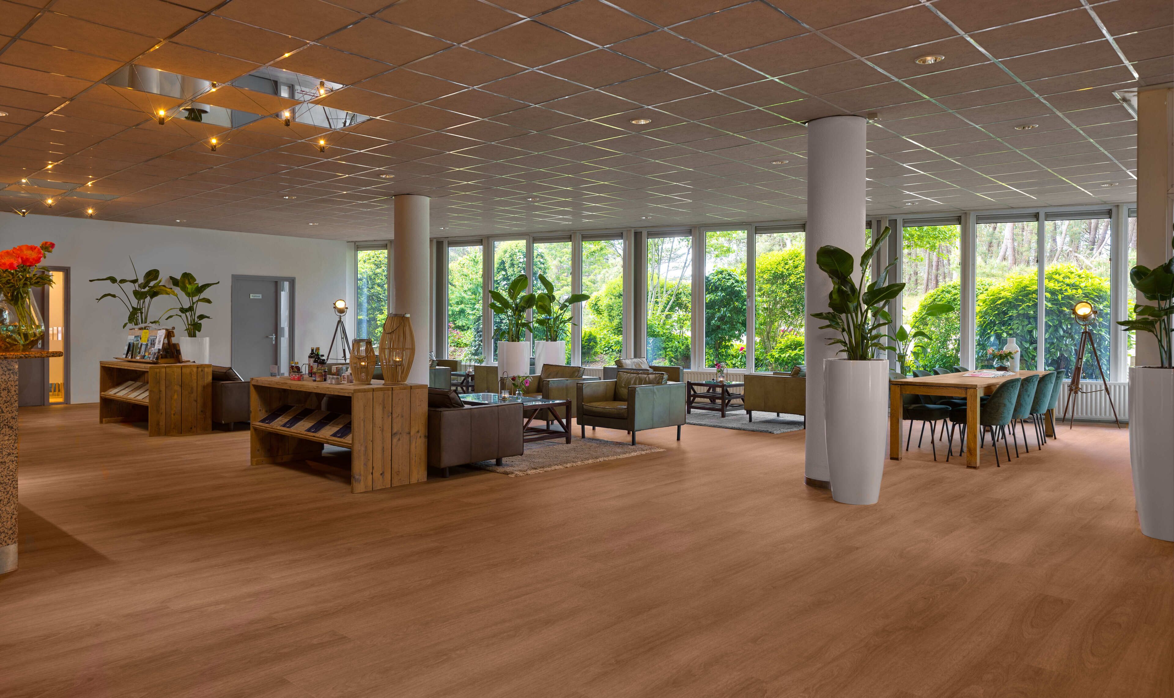 A spacious indoor area with large windows, wooden flooring, and modern furniture.