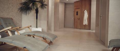 A modern spa room with wooden loungers, a large potted plant, and a wooden wardrobe.