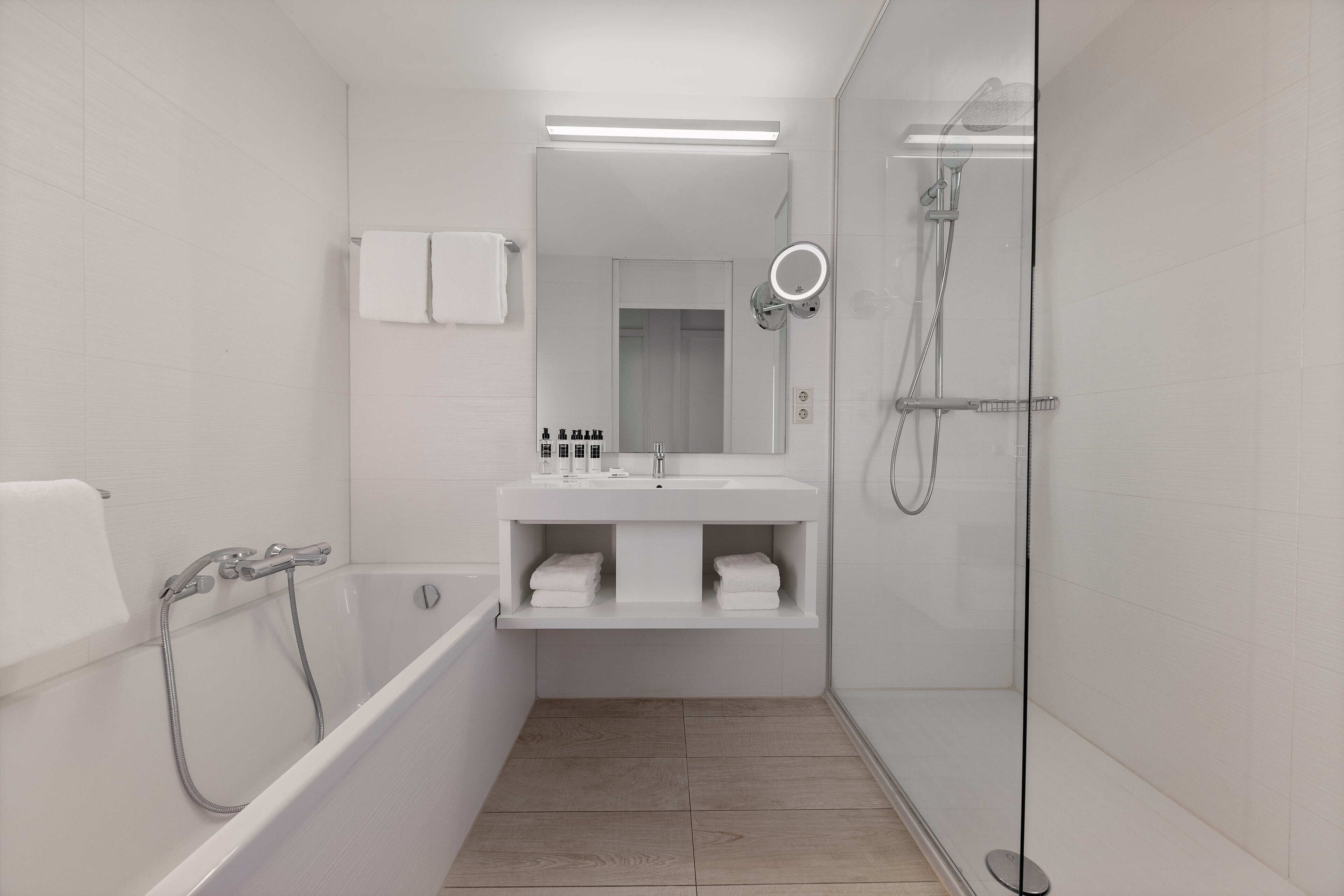 A modern bathroom with a bathtub, a glass-enclosed shower, and a vanity with a mirror.