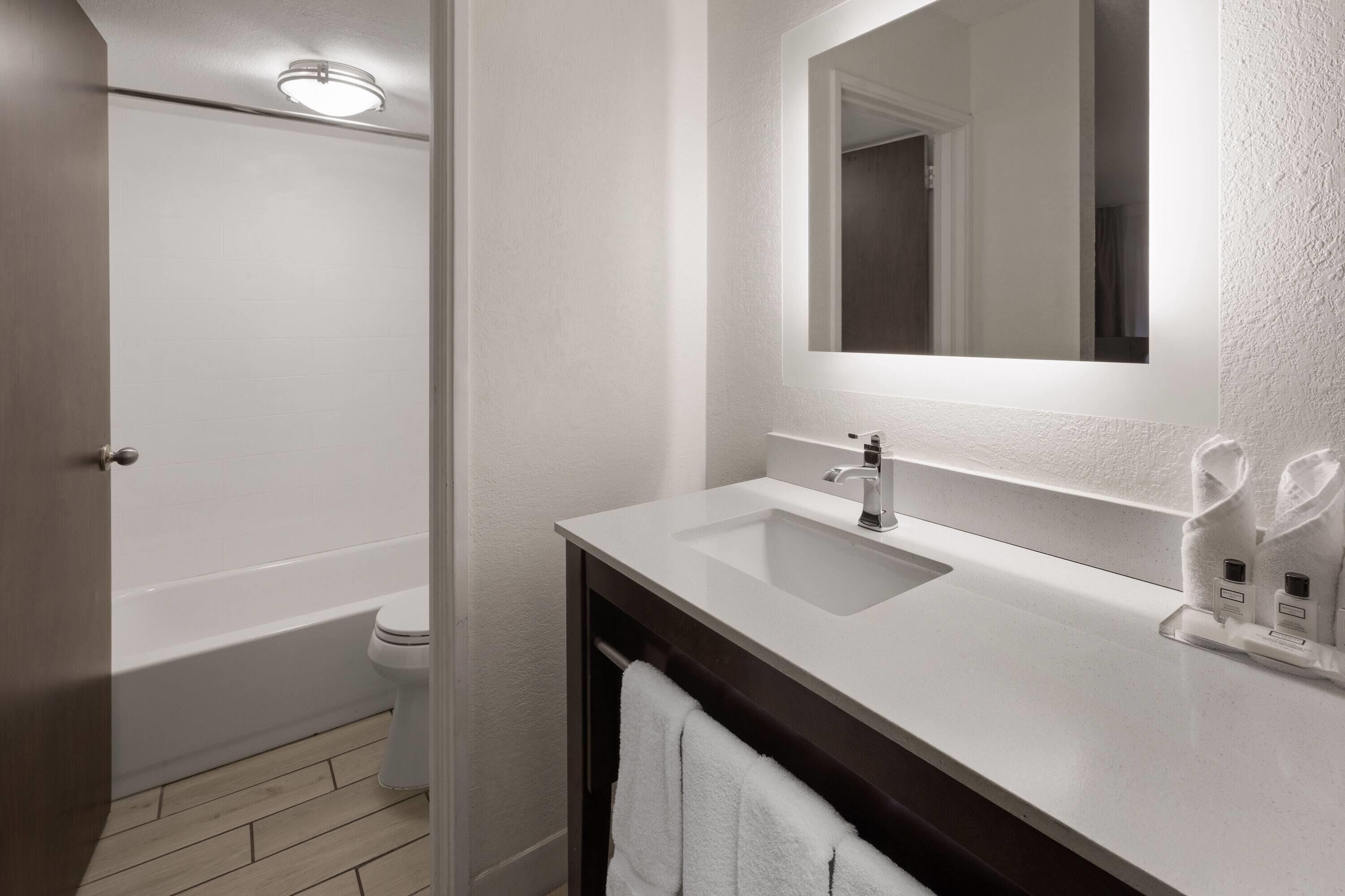 A bathroom with a white sink, mirror, and a bathtub.