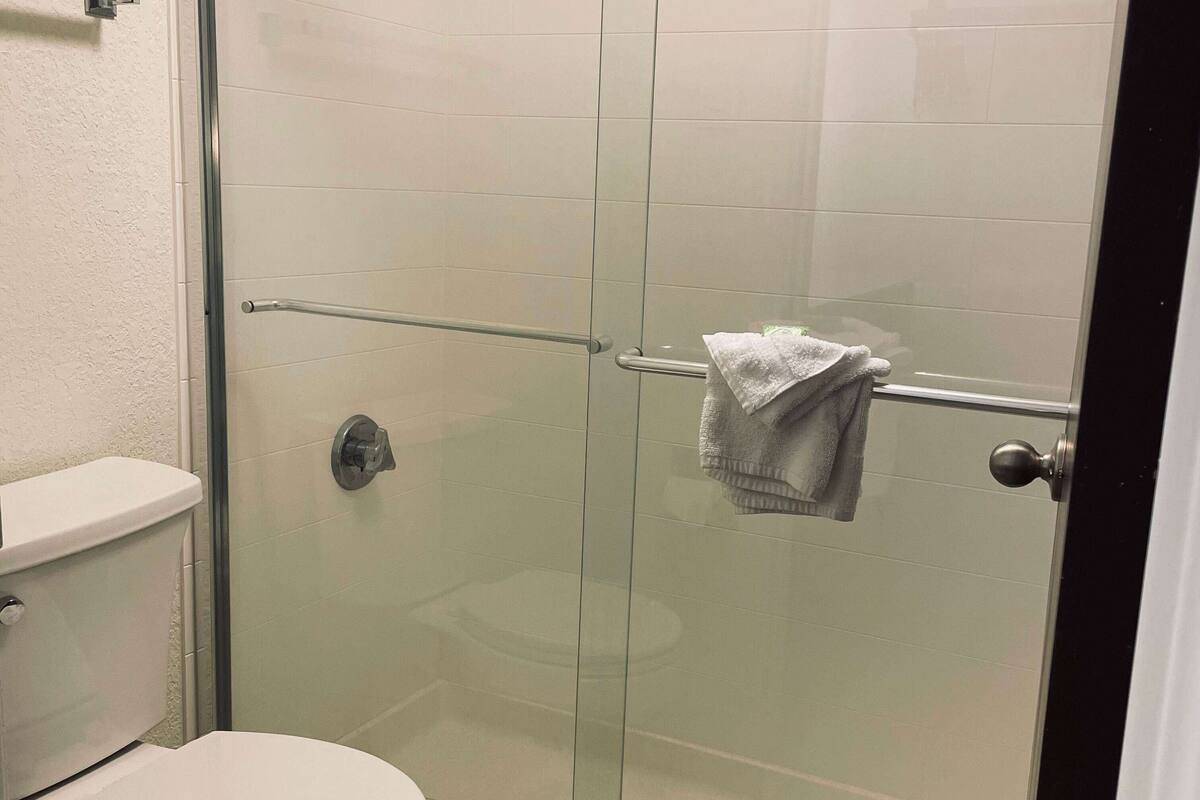 A bathroom with a glass shower enclosure, a toilet, and a towel rack with a towel.