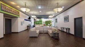 A spacious lobby with a large sectional sofa, a small round table, and a sign for 'Palm's Café Restaurant & Lounge.'