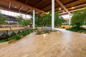 An indoor atrium with a high ceiling, wooden beams, and a central garden area. - Wyndham Garden Romulus Detroit Metro Airport (Romulus)