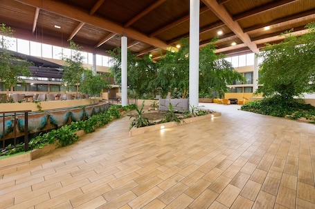 An indoor atrium with a high ceiling, wooden beams, and a central garden area.