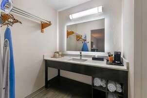 Un baño moderno con lavamanos doble, espejo con iluminación integrada, toallero y repisa con toallas dobladas con orden.