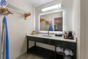 A modern bathroom with a double sink, a mirror with integrated lighting, a towel rack, and a shelf with neatly folded towels. - Quality Inn & Suites Live Oak I-10 Exit 283 (Live Oak)