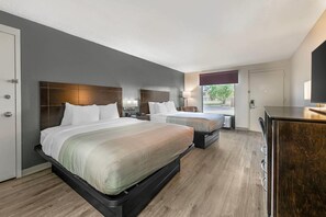 A hotel room with two beds, a desk, a chair, a lamp, and a view of the outdoors. - Quality Inn & Suites Live Oak I-10 Exit 283 (Live Oak)