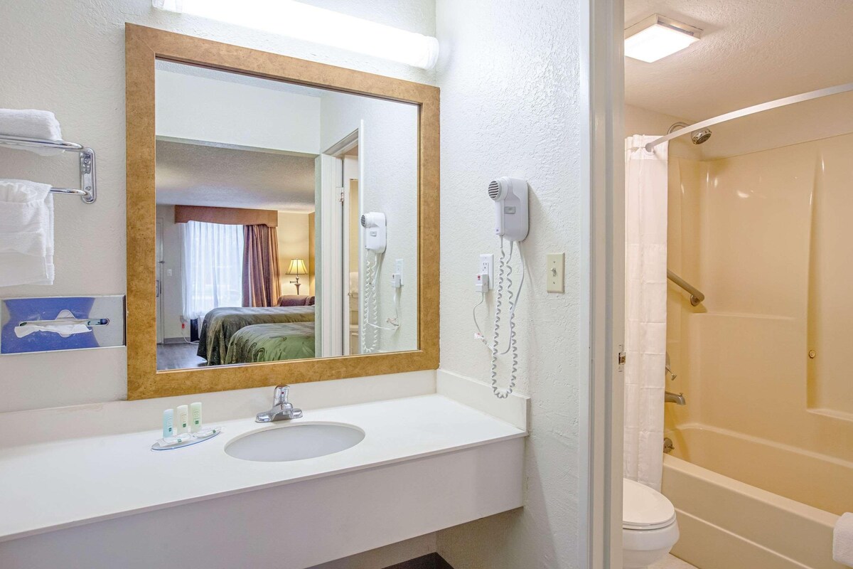 Baño con lavamanos, espejo, secador de pelo y ducha.