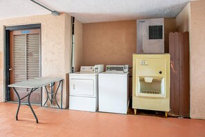 A laundry area with a table, two washing machines, and an ice dispenser. - Quality Inn & Suites Live Oak I-10 Exit 283 (Live Oak)