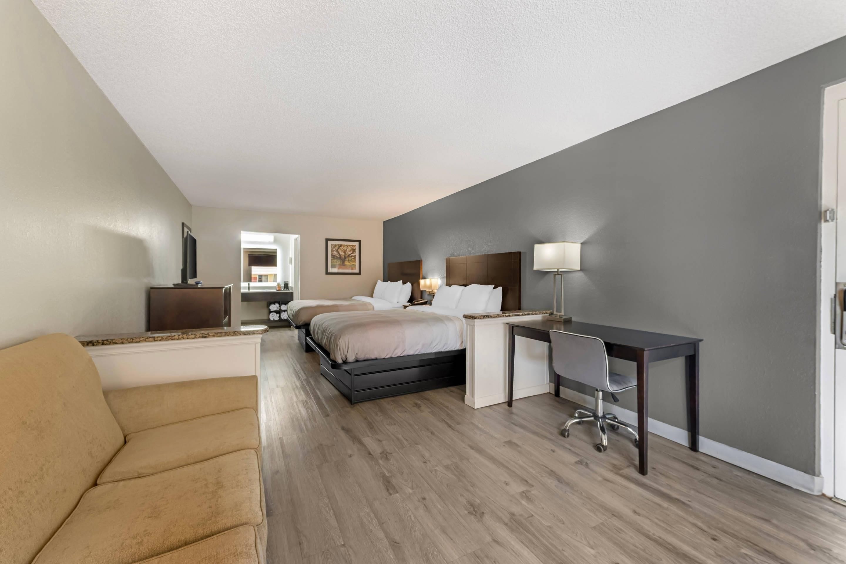 Una habitación de hotel con cama, escritorio, silla y sofá.