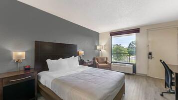 Camera d'albergo con un letto grande, abat-jour, una sedia, una scrivania e una finestra con vista.