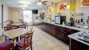 Un restaurante con mostrador, sillas, mesas, ventiladores de techo y un televisor.