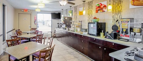 Un restaurante con mostrador, sillas, mesas, ventiladores de techo y un televisor.