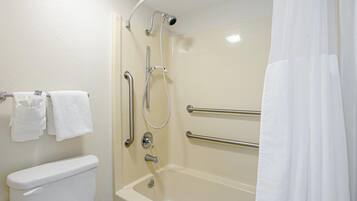 A bathroom with a bathtub, a toilet, and a shower with grab bars.