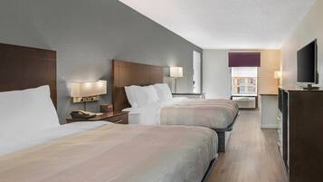 A hotel room with two beds, bedside lamps, a desk with a telephone, and a television.