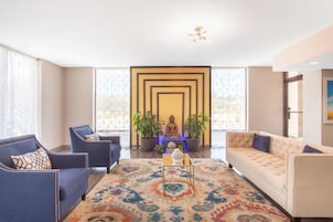 A modern living room with a sofa, armchairs, a patterned rug, and a Buddha statue.