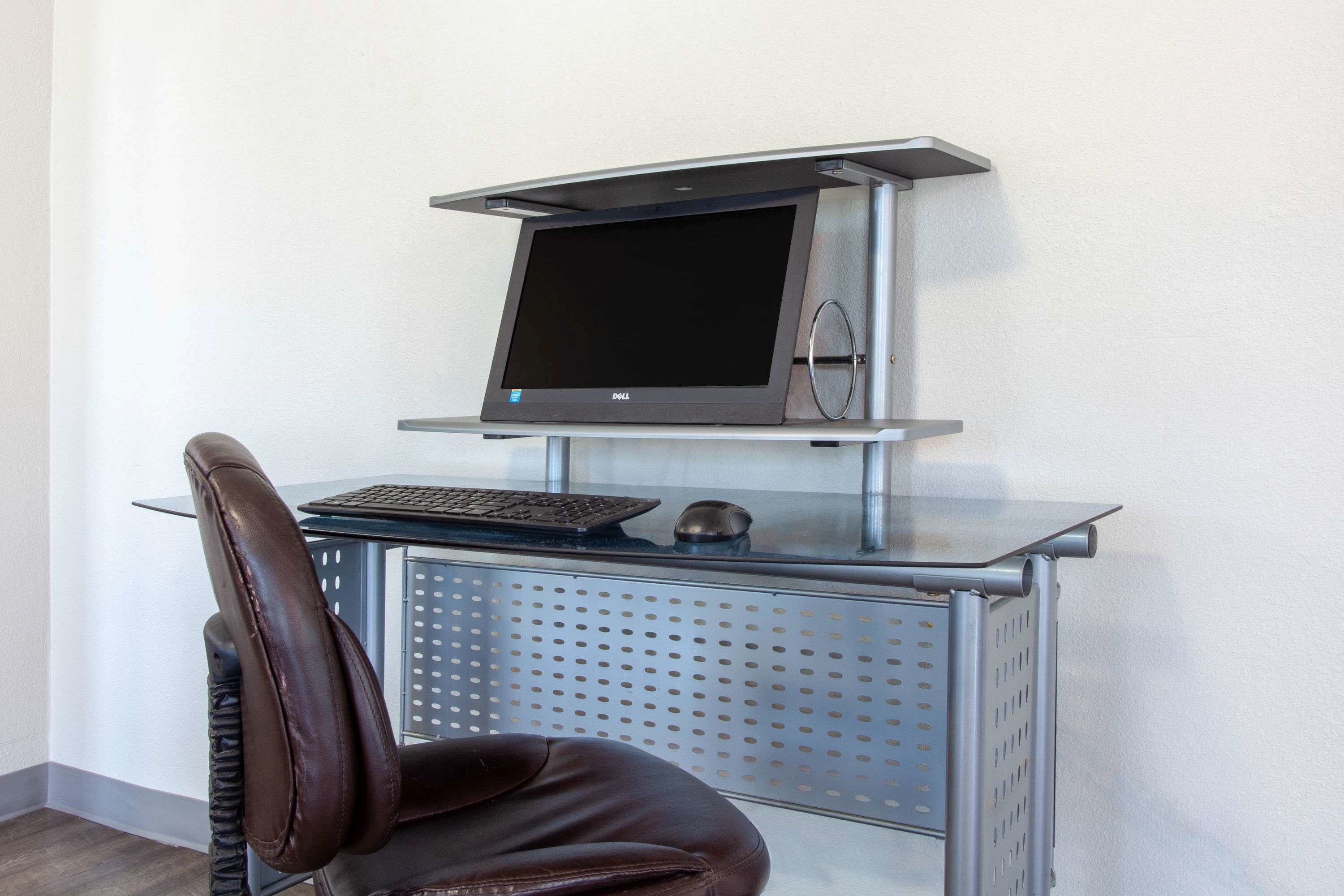 A modern office setup with a computer monitor, keyboard, and mouse on a metal desk.