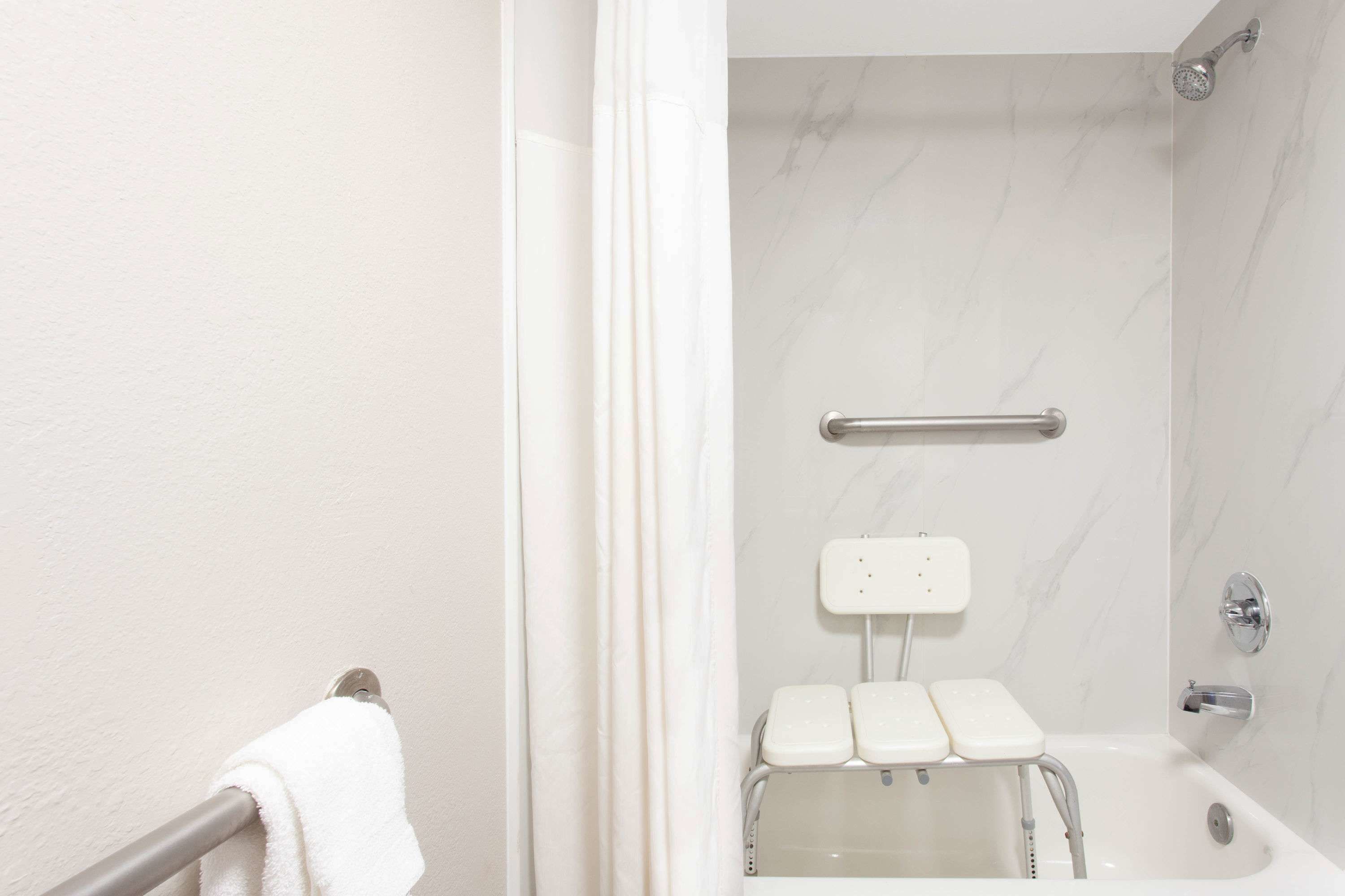 Baño con una bañera blanca, ducha y barra de apoyo.