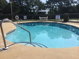 A swimming pool with a lifeguard chair, a shallow water sign, and a no diving allowed sign.