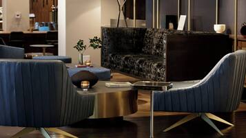 A modern living room with a dark-colored sofa, two blue armchairs, a round coffee table, and a floor lamp.
