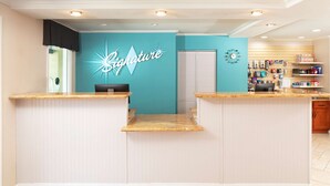 A reception area with a teal wall, a 'Signature' sign, and a counter with a computer.