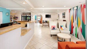 A hotel lobby with a reception desk, seating area, and a TV mounted on the wall.