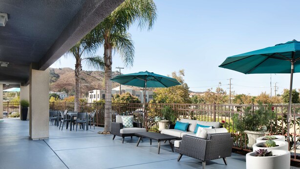 An outdoor patio area with seating, umbrellas, and potted plants.