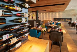 A restaurant with a wine wall, wooden tables, and chairs.