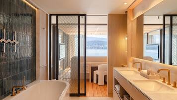 Un baño moderno con bañera, dos lavamanos y un espejo grande.