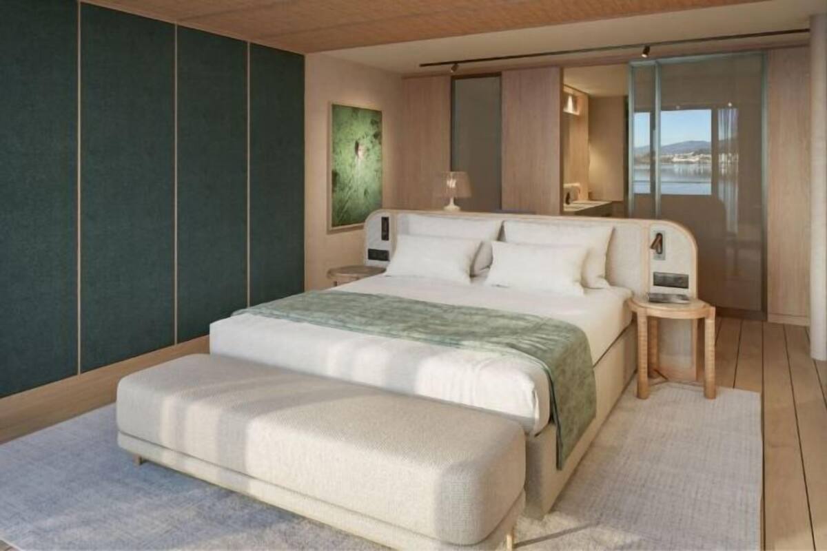 A modern bedroom with a large bed, bedside tables, a nightstand, a mirror, and a view of the outdoors.