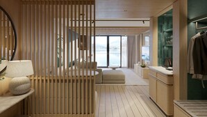 A modern hotel room with a wooden partition, a sofa, a dining area, and a view of the sea. - HERMITAGE Lake Lucerne - Beach Club & Lifestyle Hotel (Lucerne)