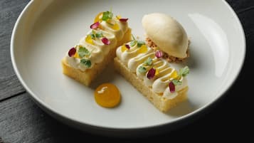 Un plato de postre con dos porciones de pastel y una bola de helado, decorado con flores comestibles.