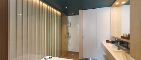 A modern bathroom with a large bathtub, a shower area, and a vanity with a mirror.
