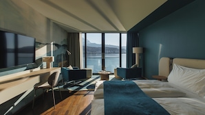 A modern hotel room with a large bed, a desk, a chair, and a TV. - HERMITAGE Lake Lucerne - Beach Club & Lifestyle Hotel (Lucerne)