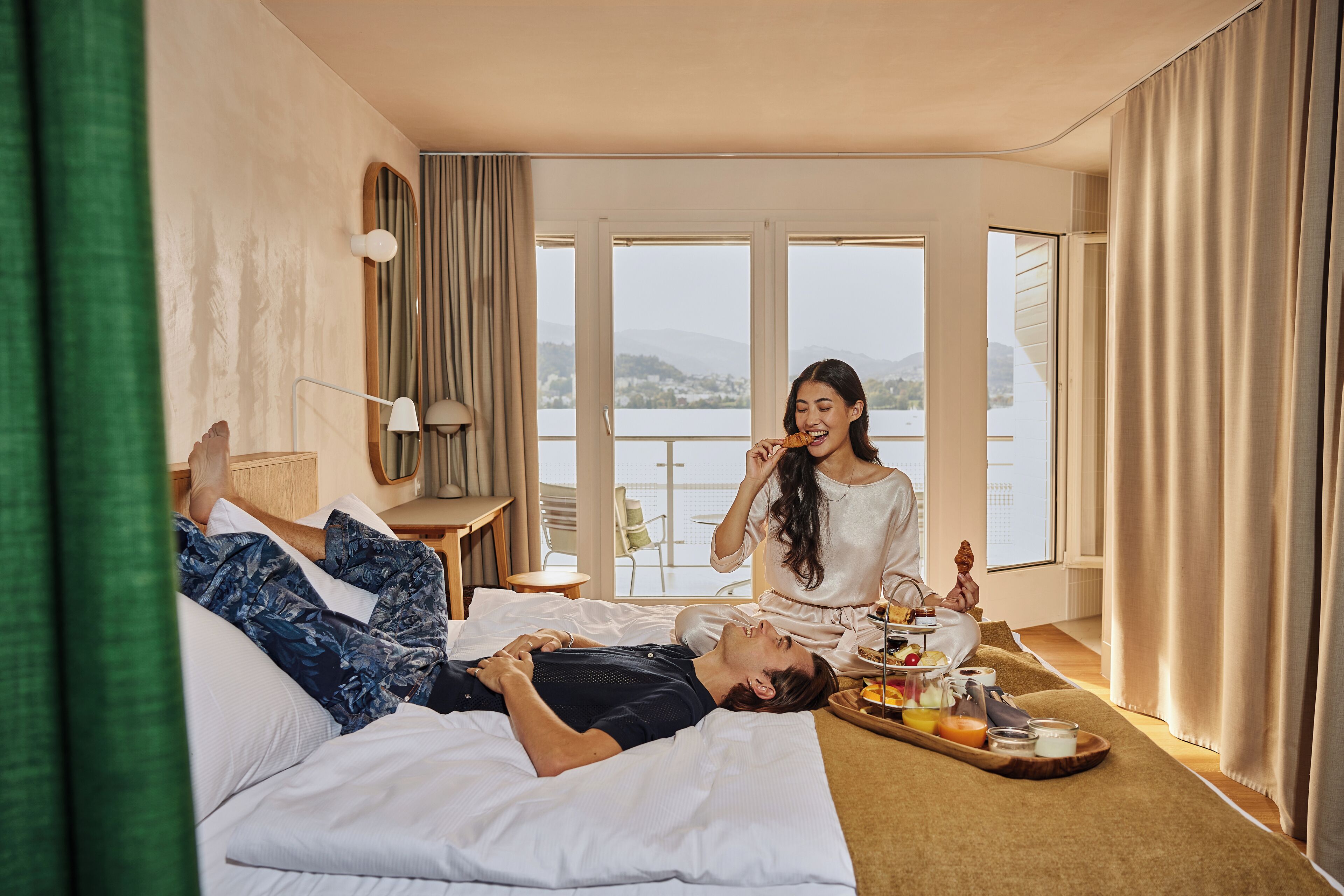 Une chambre d'hôtel avec un lit, un plateau de petit-déjeuner et une vue sur un lac.