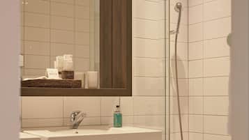 Une salle de bain moderne avec une douche à parois de verre, un lavabo blanc et un meuble-lavabo en bois.