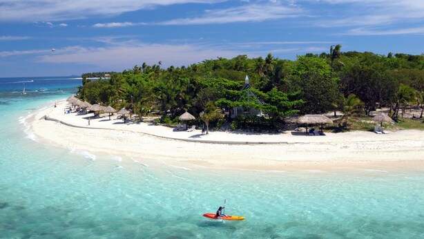 A beach with clear turquoise waters, a sandy shore, and a small island with trees and a building. - Nakelo Treasure Island Resort & Spa (Treasure Island)